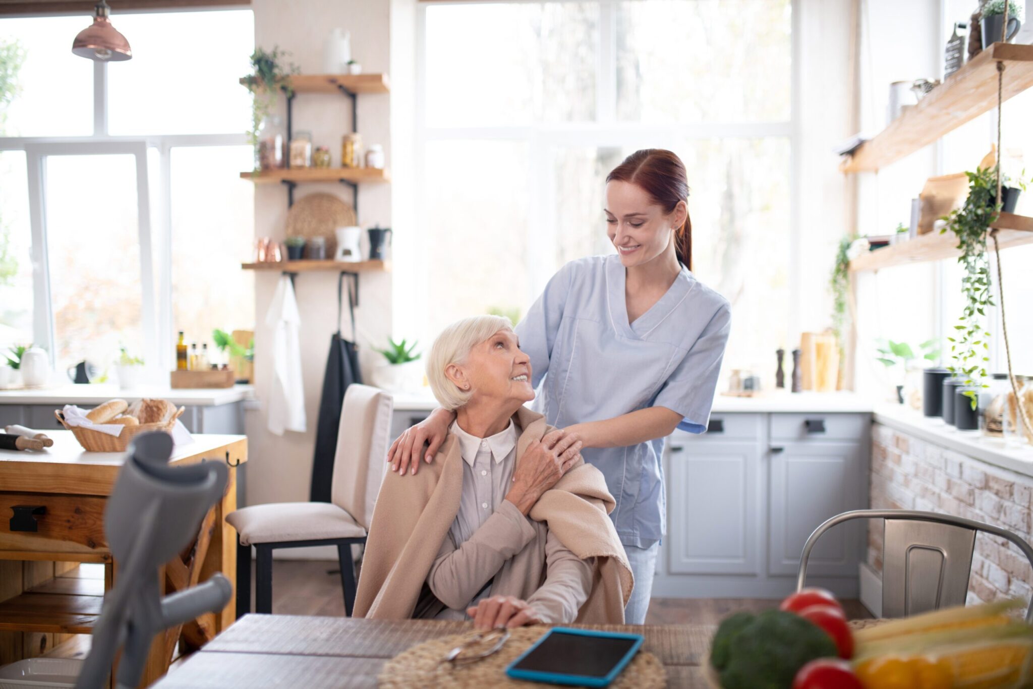 Aged pensioner feeling thankful to her pleasant caregiver Pensioner feeling thankful. Aged grey-haired pensioner feeling thankful to her pleasant caregiver